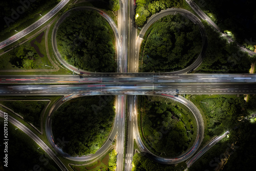 Aerial view of symmetrical highway interchange at night with vibrant light trails