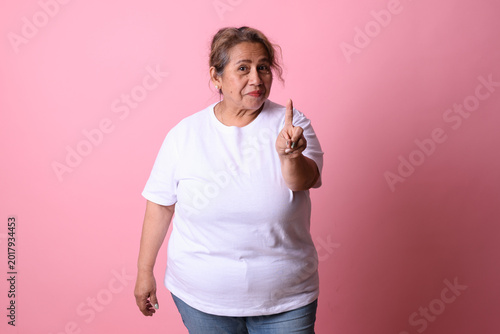 Fotografie Senior Latina Woman Gesturing No with Index Finger on Pink Background