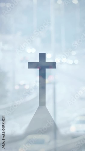 Vertical video: Cars passing sparking haze, lights glaring behind cross standing, creating contrast