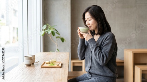 Woman enjoying a warm cup of matcha tea at a cafe by the window