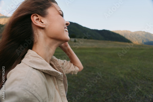 Fotografie Cheerful woman outdoors, smiling in a sunlit field, relaxed posture, soft breeze
