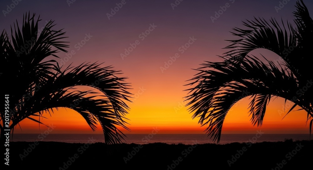 Obraz premium Silhouetted Tropical Palm Leaves Against A Vibrant Sunset Over The Ocean