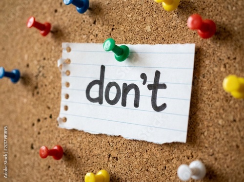 Note with word dont pinned on corkboard with colorful thumbtacks. Simple paper message implies prohibition or a negative instruction for office or school use. Notice Board Communication & Restrictions
