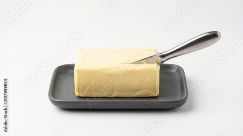 Butter block with knife on ceramic dish, ready for spreading