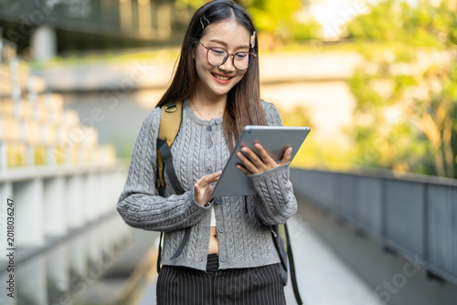 Asian happy woman using digital tablet for e-learning and studying online, Smiling female student taking online course on the internet, Modern education and mobile learning technology concept