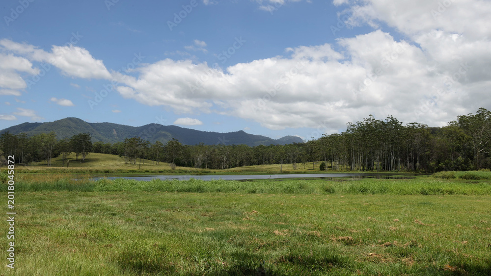 Obraz premium Serene Landscape with a Small Lake and Distant Blue Mountains