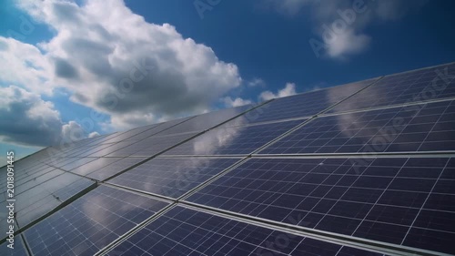 Solar panels installed on a rooftop under a cloudy blue sky