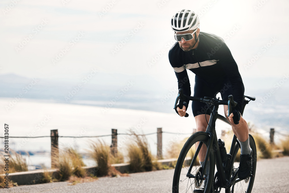 Obraz premium Fitness, cycling or person on road with bike, endurance training or challenge in cardio workout. Serious, space or cyclist outdoor with bicycle, physical activity or riding practice in sports hobby.
