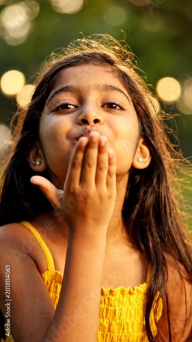 Happy Indian Little Girl Blowing a Flying Kiss in Sunny Park. Vertical video