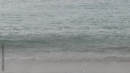 Gentle waves softly lapping on a serene sandy beach, creating a calming natural background for relaxation and coastal themes.