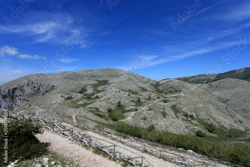 Tableau sur toile Winding Hiking Path with Wooden Fence on the Rocky Slopes of Mount Redentore
