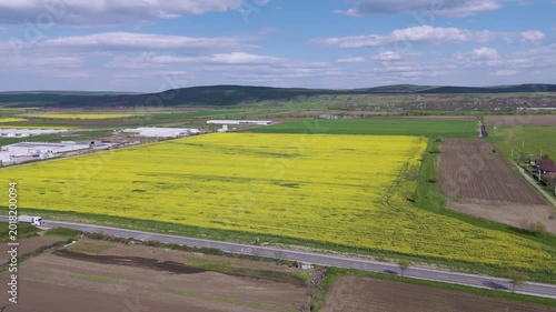 Aerial Landing Shot Over Road with Traffic and Yellow Rapeseed Fields