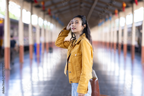 Asian woman traveler waiting at train station platform.