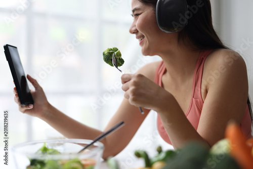 Foto Happy woman video calling while eating healthy salad.