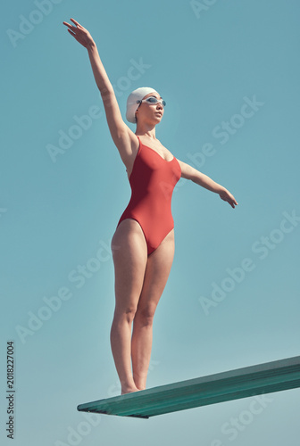 Canvastavla Diving board, woman and athlete by blue sky for swimming, exercise or sport in swimwear by space