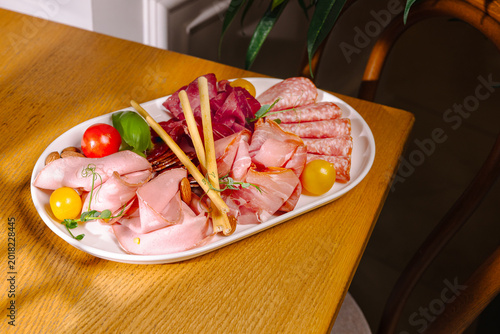 Platter of assorted meats and vegetables on a wooden table displayed in a home