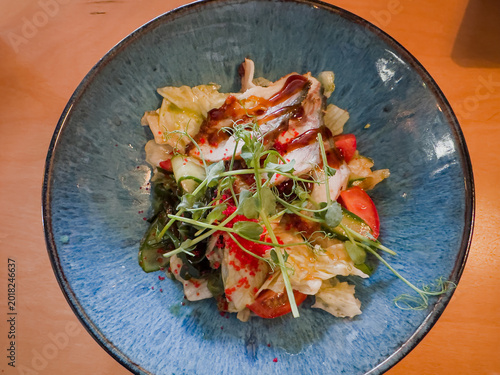 A Colorful Salad Bowl Featuring Fresh Vegetables, Greens, and a Tangy Dressing Ideal for a Healthy Meal or Snack Option, Beautifully Presented in a Deep Blue Dish