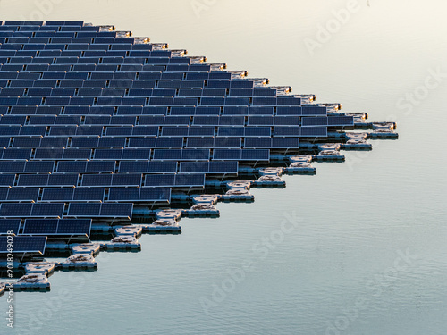 Aerial view of floating photovoltaic system with rows of solar panels on white floats over calm water during golden hour Bensheim, Hessen, Germany.