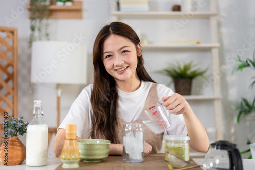 Portrait of Asian woman whisking matcha tea in a traditional bowl. 