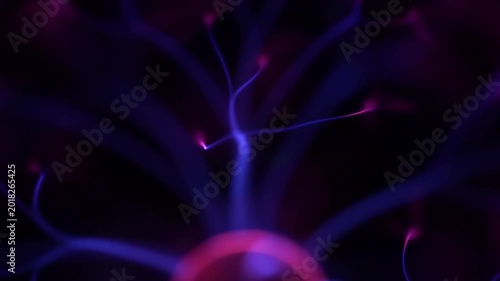 High angle view of a glowing pink electrode emitting multiple blue electric plasma arcs that fill the glass sphere with constant flickering energy.