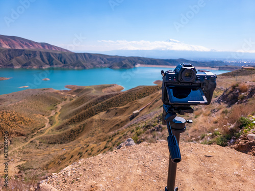 Photographer's setup overlooks beautiful alpine lake with clear blue skies