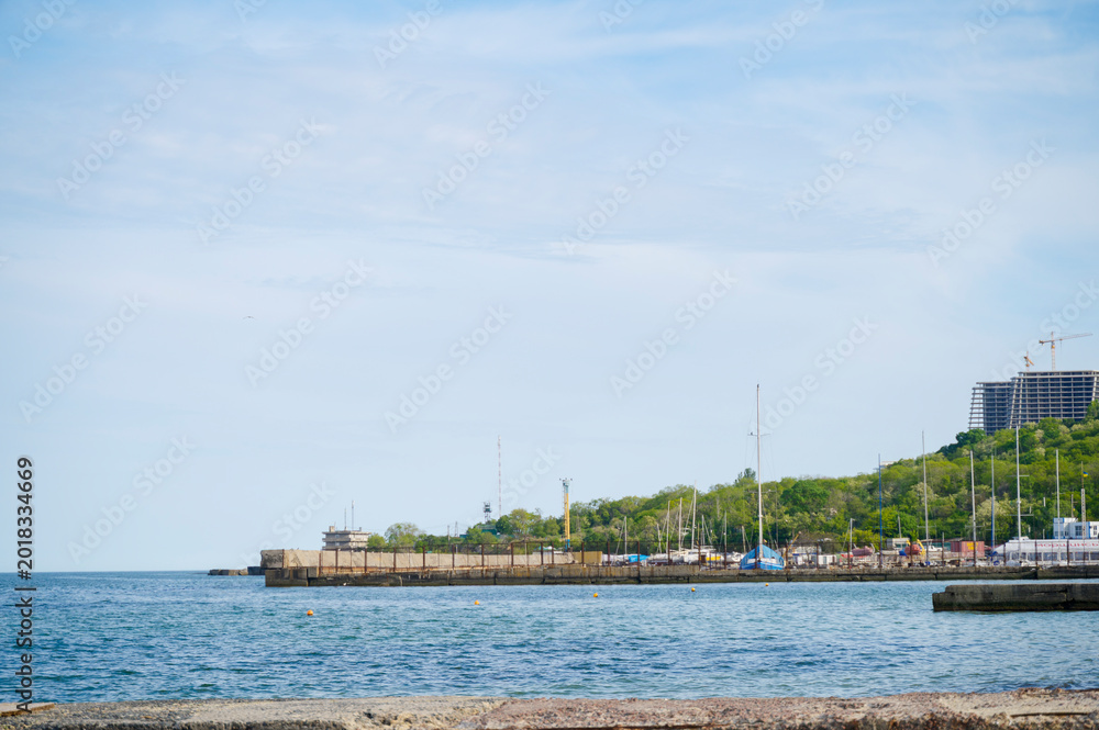 Fototapeta premium Scenic coastal view of a wooden pier and distant city under a bright sky