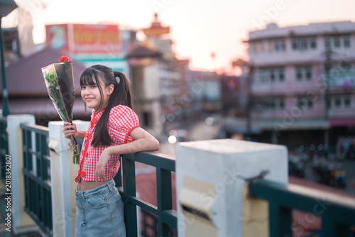 Young girl holding flower bouquet enjoying sunset cityscape view outdoors