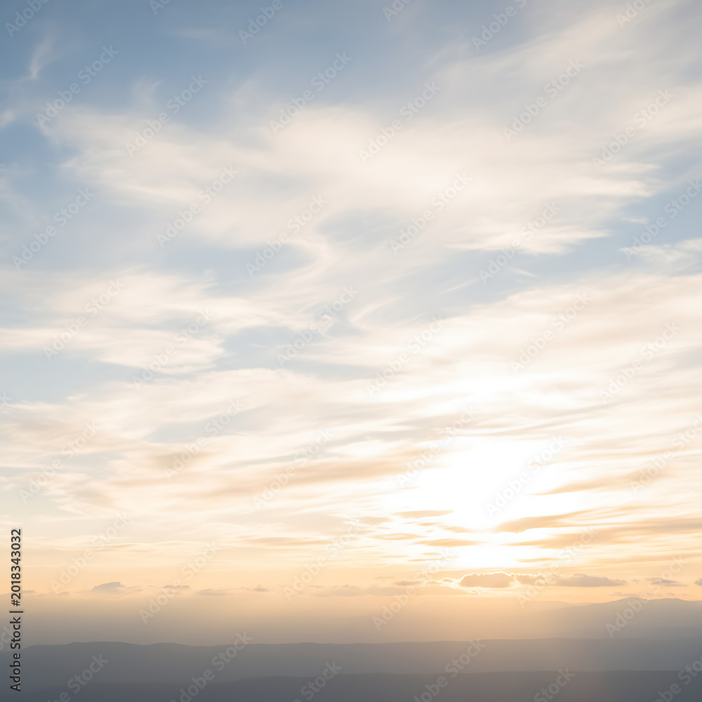 Fototapeta premium Beautiful sunset sky with soft clouds over a distant mountain range landscape