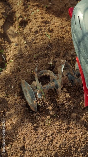 Closeup of cultivator blades turning loose garden soil