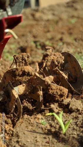 Closeup of cultivator blades covered with fresh soil