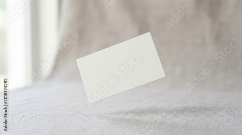 Blank white business card levitating on soft background