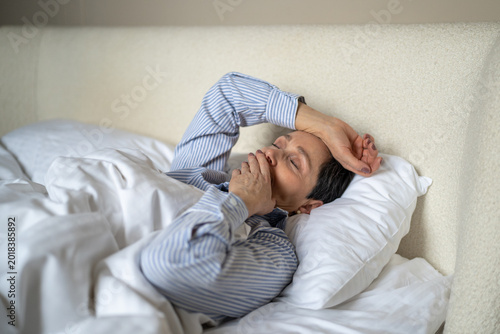 Foto Dreamy senior woman comfortably lying in bed covered in cozy blanket and yawning after waking up in morning, sleepy lazy elderly female awakening at early hours after good night rest and sweet dream