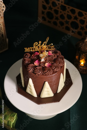 Chocolate cake (sponge, mousse, crunch, sauce) arranged artistically and separated on the plate, with Eid Mubarak topper.