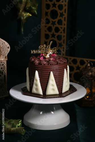 Chocolate cake (sponge, mousse, crunch, sauce) arranged artistically and separated on the plate, with Eid Mubarak topper.