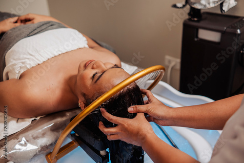 Young asian lady receiving aqua ring water halo scalp rinse at a Japanese head spa for scalp cleansing, relaxation, hydration, and soothing hair therapy.
