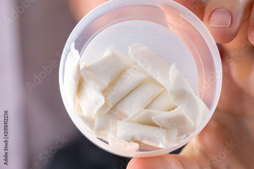 Cuadro en lienzo closeup of a hand holding an open round white plastic container filled with smal