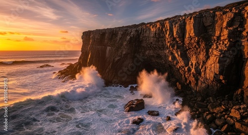 Dramatic Sunset Over Rugged Coastal Cliffs with Crashing Waves.