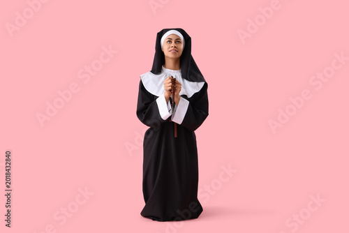 Картината върху платно Young nun with beads praying on pink background