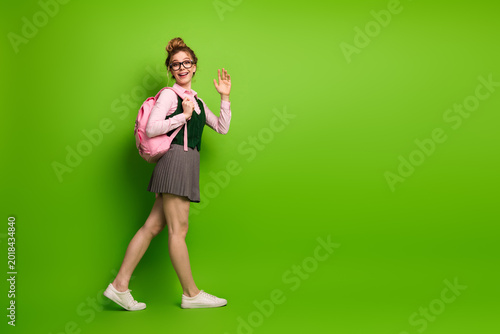 Foto Teenage girl ready for school standing on a vibrant green background, holding a