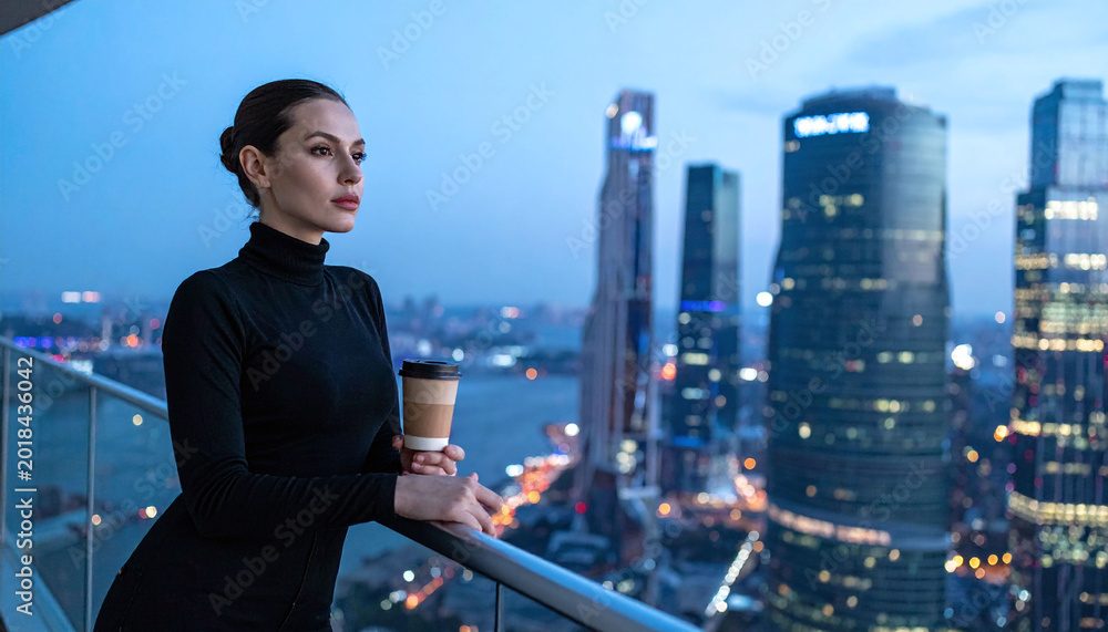Naklejka premium A thoughtful female professional stands on a luxury balcony with coffee, overlooking an illuminated cityscape at twilight. Ideal for business, ambition, and modern urban lifestyle themes.