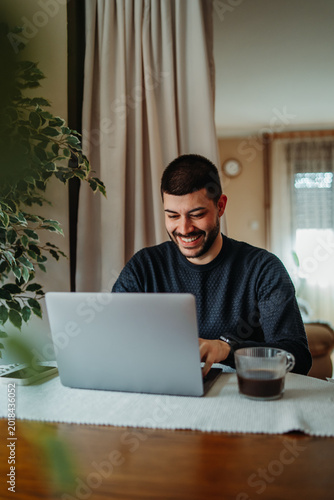 Man smiling working from home using laptop
