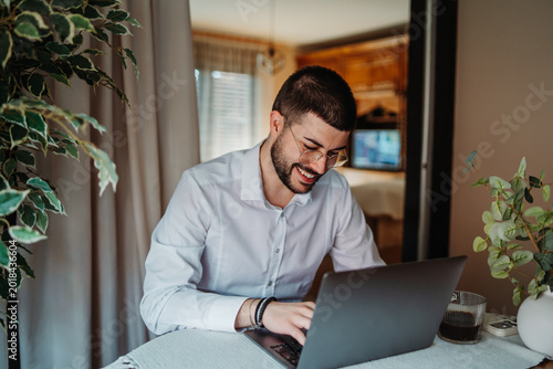 Young man happily working from home using laptop