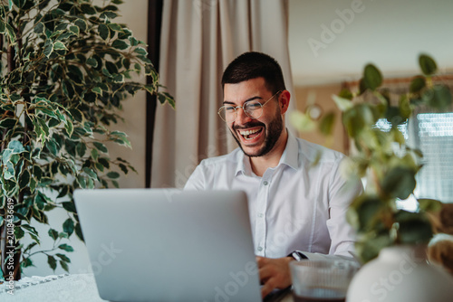 Man laughing while working from home on laptop