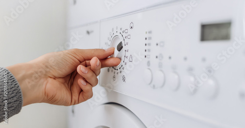 Tableau sur toile Hand of a person adjusting the settings on a modern washing machine control pane