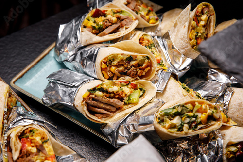 Fotografía Assorted beef and vegetable wraps wrapped in aluminum foil on a blue platter