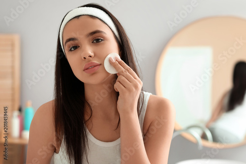 Young woman removing makeup...