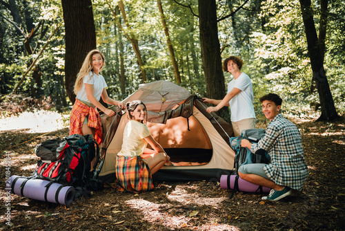 Foto Friends setting up a tent in the woods on a summer camping trip, young group enj