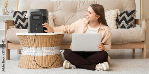 Young woman charging laptop...