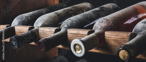 Canvas Print Wooden holder with bottles of wine in dark cellar