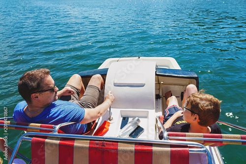 father and son rides a catamaran on vacation. Mountain lake. Family outing.